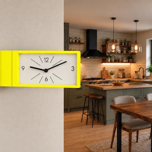 May include: A rectangular wall clock with a bright yellow frame and a white face. The clock features black numerals at the 3, 6, 9, and 12 positions, with black hour and minute hands and thin black lines marking the remaining hour intervals.