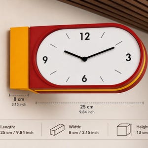 Puede incluir: Un reloj de pared horizontal con esfera blanca, números negros 3, 6, 9 y 12, y manecillas negras. El marco es rojo con una sección lateral amarilla. Las dimensiones son 25 cm de largo, 8 cm de ancho y 13 cm de alto según las indicaciones.