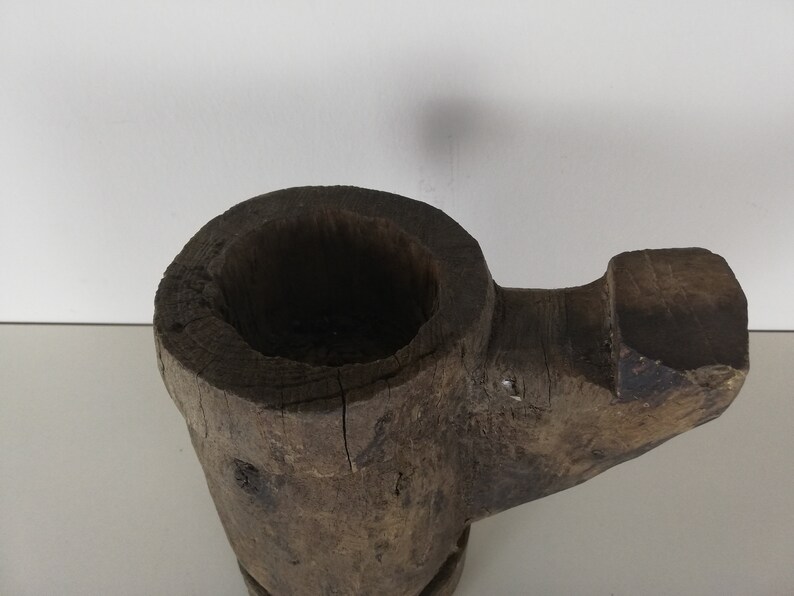 May include: A rustic wooden mortar and pestle with a dark brown finish. The mortar is shaped like a bowl with a wide opening and a rounded bottom. The pestle is a long, cylindrical piece of wood with a rounded end.