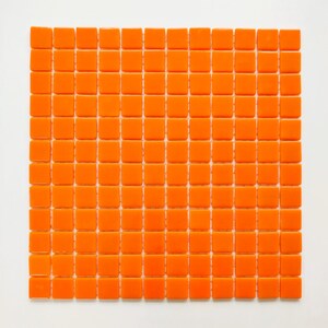 May include: A square sheet of small, glossy orange tiles arranged in a uniform grid pattern. The individual tiles are square-shaped with rounded edges, creating a consistent texture across the entire surface of the mosaic tile sheet.