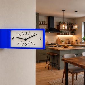 Puede incluir: Un reloj de pared rectangular con un marco azul brillante y una esfera blanca. El reloj cuenta con manecillas negras para las horas y los minutos, números negros en las posiciones 3, 6, 9 y 12, y finas líneas negras para las horas restantes.