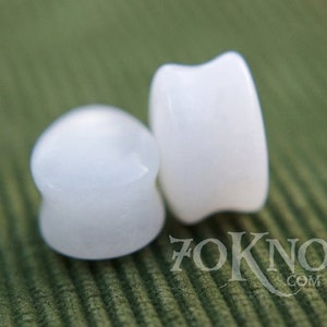 Puede incluir: Dos expansores de oreja redondos, opacos y blancos. Los expansores est&aacute;n hechos de un material liso y pulido.