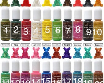 May include: Twenty bottles of pearl pigment for resin crafts. The bottles are labeled with numbers 1 through 20. Each bottle has a small bear figurine in front of it, each a different color. The colors include bronze gold, black, green, red, white, yellow, apple green, brown, multicolor red, silver black, gold, chrysoberyl, pink, rose-bengal, light pink, sapphire blue, brownish red, purple, shiny blue, green, and bronze.