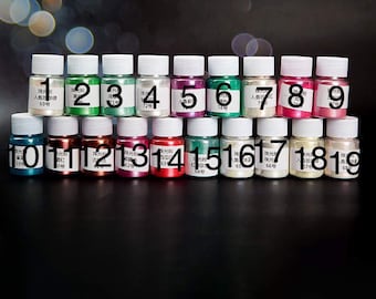 May include: Nineteen small glass bottles with white lids, each containing a different color of iridescent pigment powder. The bottles are labeled with numbers 1 through 19.