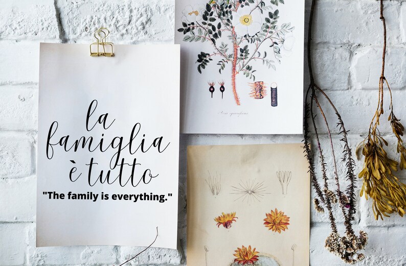 May include: A white poster with black calligraphy that reads "la famiglia &egrave; tutto" and the English translation "The family is everything."