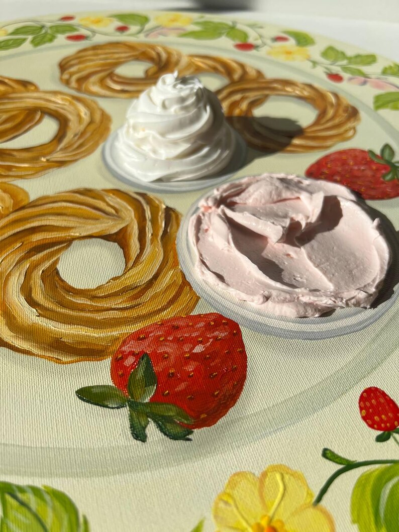 May include: A white plate with a decorative border features a variety of pastries, two bowls of whipped cream, and two strawberries. One bowl of whipped cream is white, and the other is pink.