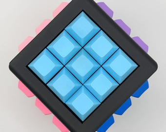 May include: A square puzzle with a black frame and nine light blue square buttons. The puzzle is surrounded by pink, purple, and blue accents. The puzzle is a brain teaser or a toy.