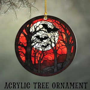 Round Acrylic Ornament, Printed in the style of Faux stained glass.  Ornament shows a haunted forest of trees against a red background.  A full moon in the distance with 3 black bats silhouetted against it.  Ornament hangs from a gold string