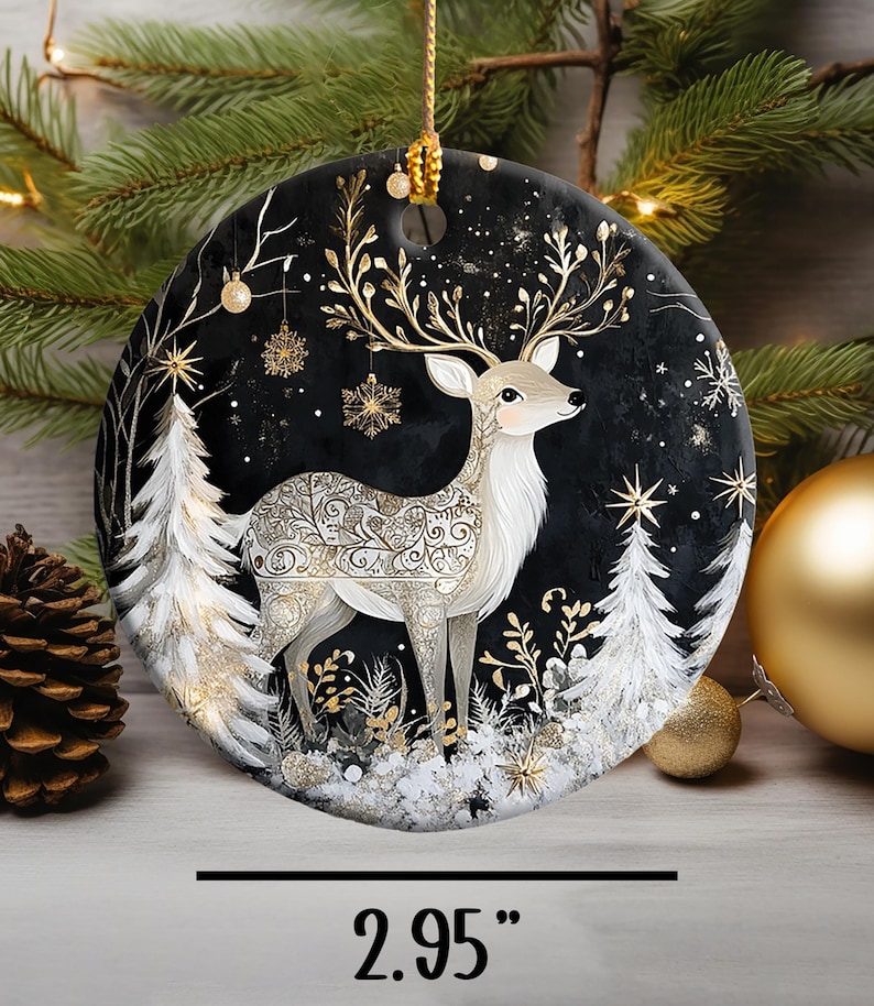 May include: A round Christmas ornament featuring a deer design. The deer has gold antlers and decorative patterns on its body, set against a black background with white trees and snowflakes. The ornament is 2.95 inches in diameter.