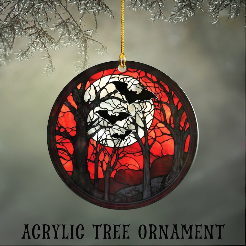 Round Acrylic Ornament, Printed in the style of Faux stained glass.  Ornament shows a haunted forest of trees against a red background.  A full moon in the distance with 3 black bats silhouetted against it.  Ornament hangs from a gold string