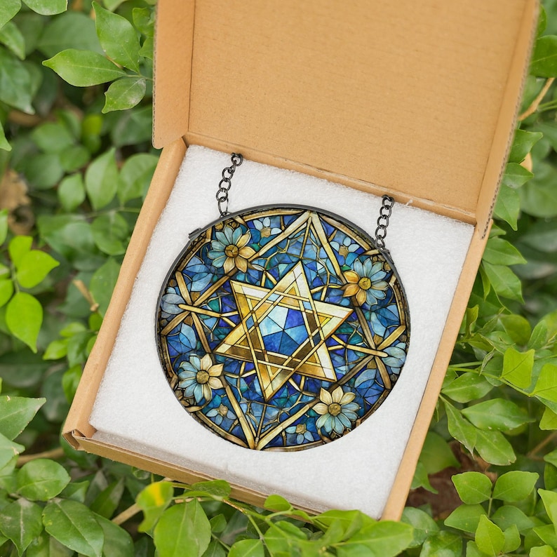 Pu&ograve; includere: Una finestra in vetro colorato appesa con una stella di David blu e dorata circondata da fiori blu e bianchi.