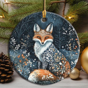 Könnte beinhalten: Ein rundes Keramikornament mit einer detaillierten Illustration eines Fuchses, dessen Fell mit komplexen weißen Mustern verziert ist. Der Fuchs ist vor einem dunkelblauen Waldhintergrund mit weißen Blumen- und Blattmotiven abgebildet.