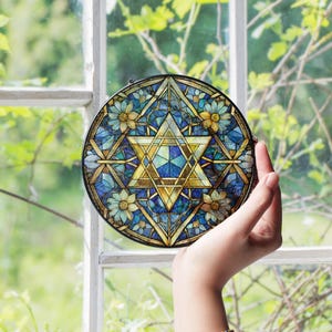 Pu&ograve; includere: Un ornamento rotondo in vetro colorato con una stella di David blu e dorata con accenti floreali.