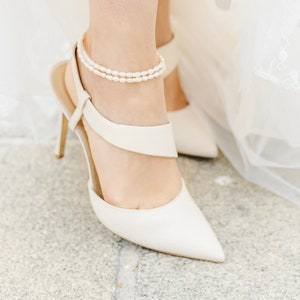 Bride modeling in white dress shoes and pearl anklets