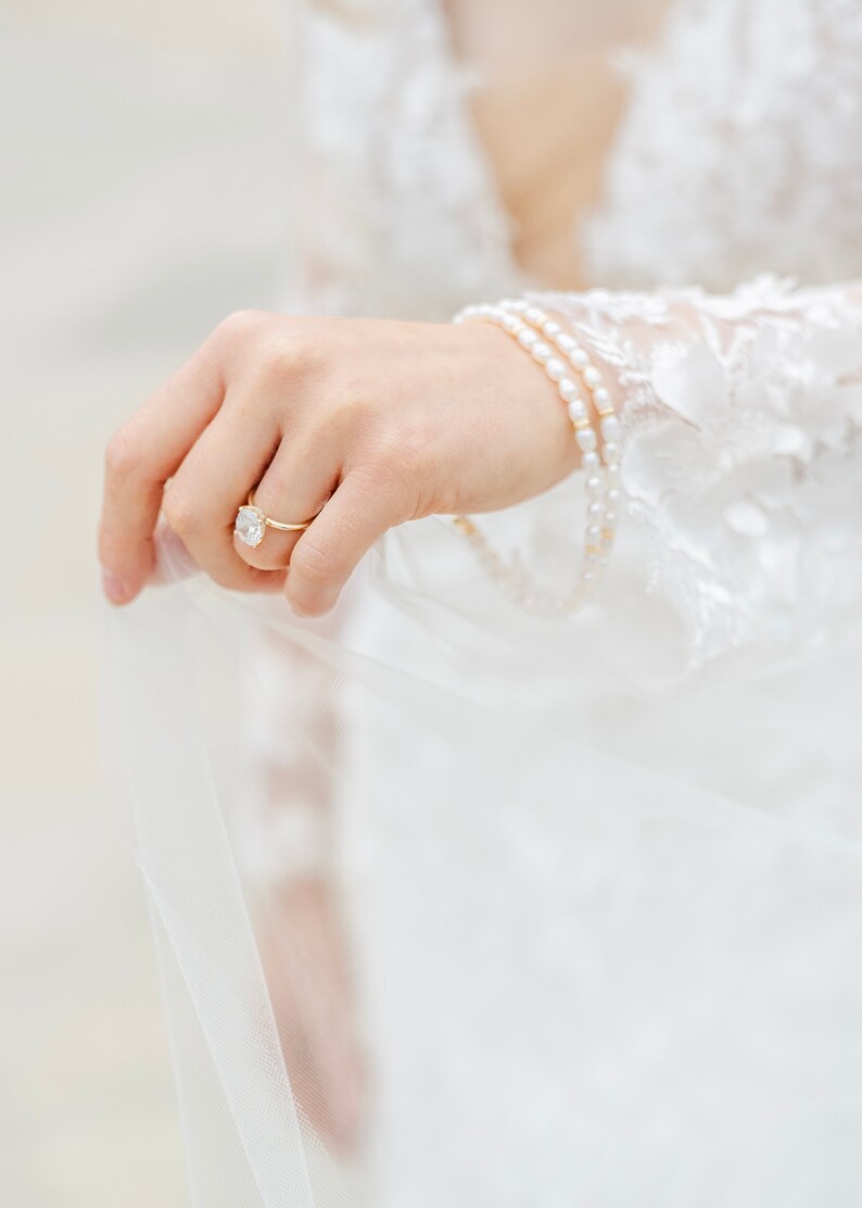 Bride holding pearl anklets in wedding dress