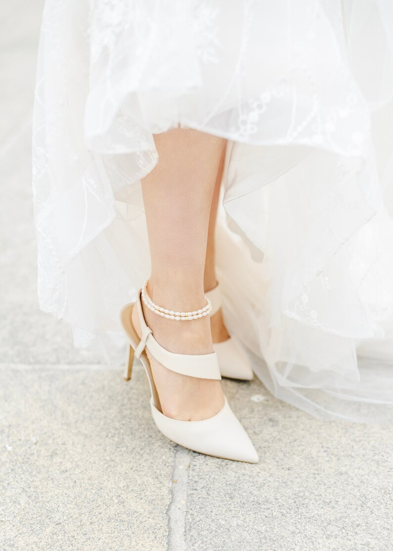 Bride modeling in white dress shoes and pearl anklets