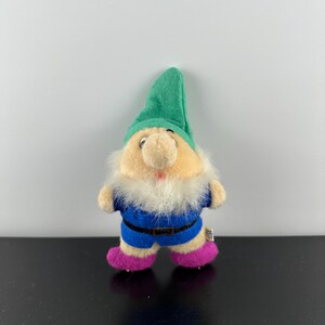 May include: A plush toy gnome with a green hat, white beard, blue shirt, and pink shoes.