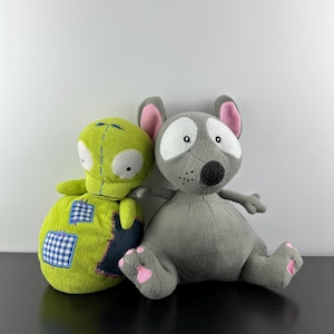 Puede incluir: Dos peluches: una criatura alienígena verde lima con ojos blancos y un ratón gris con orejas y patas rosas. El alienígena tiene un diseño de patchwork con cuadrados azules y blancos. El ratón tiene una nariz negra y manchas blancas.
