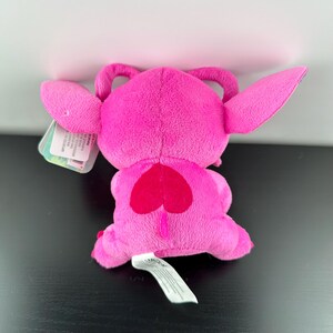 Op de afbeelding: Een felroze pluche speelgoed met grote oren, een hartvormig ontwerp op de rug en een kleine staart. Het speelgoed heeft een label bevestigd. Het pluche is gemaakt van zacht materiaal.