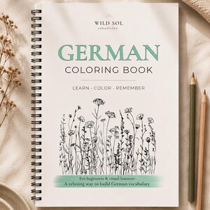 Könnte beinhalten: Ein spiralgebundenes deutsches Malbuch mit dem Titel "GERMAN COLORING BOOK" in Mintgrün. Das Cover zeigt eine schwarz-weiße Blumenillustration und den Text "LEARN • COLOR • REMEMBER". Zwei Bleistifte liegen auf der rechten Seite.