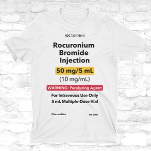 Może przedstawiać: Biała koszulka z czarnym napisem "Rocuronium Bromide Injection". Poniżej widnieje "50 mg/5 mL" w kolorze żółtym oraz "WARNING: Paralyzing Agent" w kolorze czerwonym. Koszulka zawiera również "For Intraveous Use Only" i "5 mL Multiple-Dose Vial".