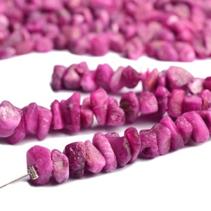 Hand holding raw ruby pieces to show size and organic shape.