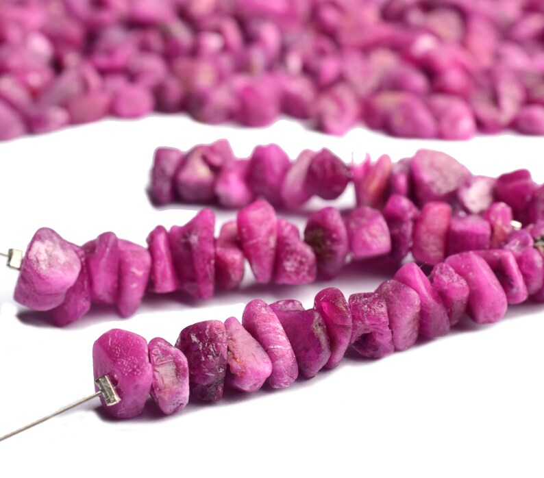 Hand holding raw ruby pieces to show size and organic shape.