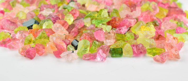 Hand-held raw tourmaline stones showing color variations and natural formation.