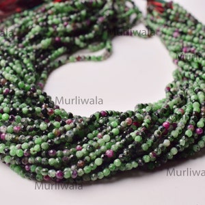May include: A strand of green, black, and pink gemstone beads. The beads are round and have a faceted finish. The strand is approximately 16 inches long.