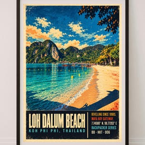 May include: A framed travel poster featuring Loh Dalum Beach in Koh Phi Phi, Thailand. The image displays a sandy beach, turquoise water, and limestone cliffs under a blue sky. Text includes "LOH DALUM BEACH", "KOH PHI PHI, THAILAND", and coordinates.