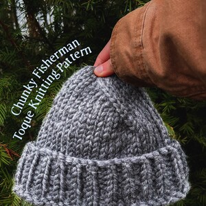 Op de afbeelding: Een grijze, dikgebreide vissersmuts, met een omgeslagen rand. De hoed is gemaakt van dik garen en heeft een getextureerd uiterlijk. Tekst op de afbeelding luidt "Chunky Fisherman Toque Knitting Pattern."