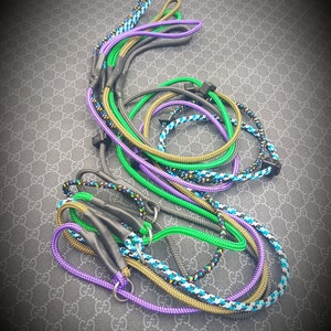 Puede incluir: Una colección de correas de cuerda de colores con detalles negros. Las correas están hechas de diferentes colores y patrones, incluyendo verde, morado, azul y negro.