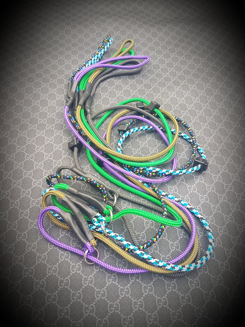 May include: A collection of colorful rope leashes with black accents. The leashes are made of different colors and patterns, including green, purple, blue, and black.