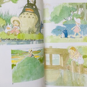 May include: Watercolor illustrations from a book featuring characters from the animated film "My Neighbor Totoro." The images depict scenes with Totoro, a large forest spirit, and a young girl in various outdoor settings, with a soft, whimsical style.
