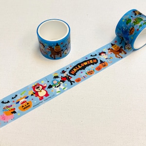 May include: A roll of light blue decorative adhesive tape featuring a repeating pattern of Disney Pixar characters in Halloween costumes, including pumpkins, bats, and the text HALLOWEEN. One roll is standing upright, and another is unrolled.