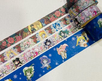 May include: Three rolls of decorative adhesive tape featuring anime-style character illustrations and floral patterns. One roll displays pink roses, another shows various anime figures with flowers, and the third is blue with character portraits.