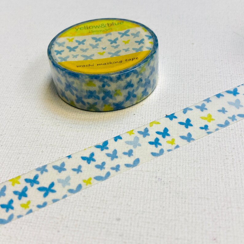 May include: A roll of washi tape with a blue and yellow butterfly pattern. The tape is labelled "yellow & blue 15mm washi masking tape".
