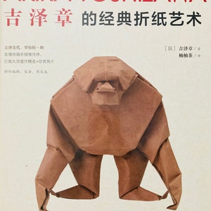 May include: A book cover with a brown origami gorilla on a white background. The title of the book is "Akira Yoshizawa's Classic Origami Art" in red and black text. The book is written in Japanese and translated into English.