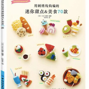 May include: A book cover with a colorful illustration of crocheted food items. The book title is "Miniature Sweets & Food 70 Designs" in Japanese. The book cover features a variety of crocheted food items, including a donut, a baguette, a cake, a strawberry shortcake, a sushi roll, and a fried chicken.