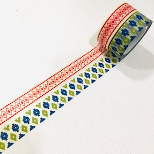 Könnte beinhalten: Zwei Rollen dekoratives Klebeband. Eine Rolle zeigt ein geometrisches Rautenmuster in Rot auf cremefarbenem Grund. Die zweite Rolle zeigt ein sich wiederholendes Muster aus blauen und grünen Rauten und Kreuzformen auf weißem Grund.