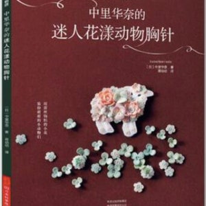 Könnte beinhalten: Ein Buchcover mit rotem Hintergrund und einem weißen Lamm aus Blumen. Der Titel des Buches lautet "中里华奈的 迷人花漾动物胸针" in chinesischen Schriftzeichen.