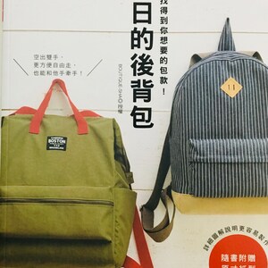 以下が含まれることがあります： 緑と白のストライプのキャンバス地のバックパックが2つ。緑のバックパックは赤いジッパーと赤いストラップ。青いバックパックは前面に茶色の革のパッチ。画像のテキストは「每日的後背包」で、「普段使いのバックパック」と訳されます。