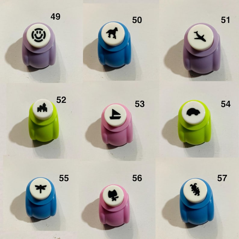 May include: A collection of nine colorful craft paper punches labeled 49 through 57. Each punch features a unique black icon on a white circular top, including a smiley face, horse, airplane, castle, sailboat, car, dragonfly, cat, and rabbit.