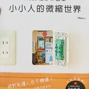 May include: A book cover with the title "The Tiny World of Kobito" in white text on a black background. The book cover features a miniature room scene inside a light switch, with a red car, a computer, and a chair. The book cover also features the text "Mozu 袖珍作品集" in black text on a white background, and the text "小小人的微縮世界" in black text on a white background.