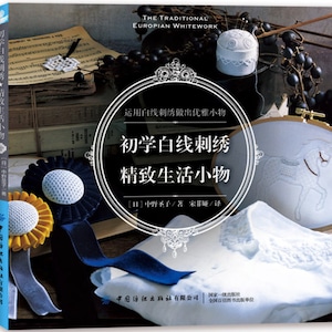 Pode incluir: Capa de livro com fundo branco e fita azul. O título é "Bordado branco para iniciantes: Coisas pequenas e requintadas da vida" em texto preto. A capa do livro apresenta um cavalo branco bordado em um tecido branco.