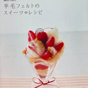 May include: A book cover featuring a felted dessert parfait in a clear glass. The parfait includes red strawberries, a cherry, and vanilla ice cream. The book title is in Japanese.