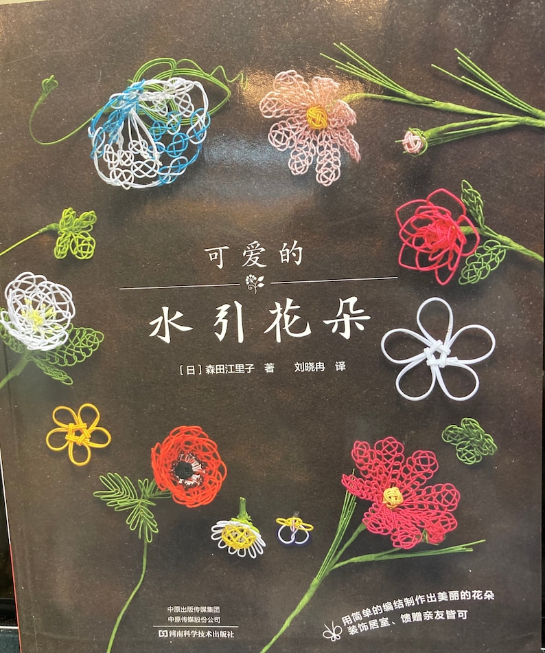 May include: A book cover with the title "Cute Water Ribbon Flowers" in Japanese. The cover features colorful water ribbon flowers in various shapes and sizes, including a daisy, a rose, and a clover.