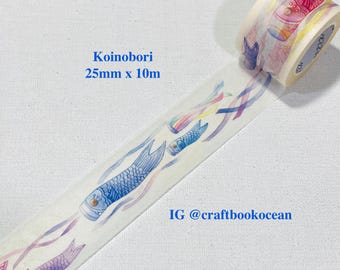 Könnte beinhalten: Dekoratives Washi-Tape mit Koinobori-Design, das blaue, violette und rosa Karpfen-Wimpel zeigt. Das Klebeband ist 2,5 cm breit und 10 m lang. Die Rolle ist teilweise abgerollt und zeigt das sich wiederholende Muster.