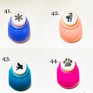 May include: Four craft paper punches labeled 41 through 44. Number 41 is blue with a snowflake icon, 42 is peach with a cat icon, 43 is teal with a bird icon, and 44 is magenta with a paw print icon. Each punch has a white top plunger.