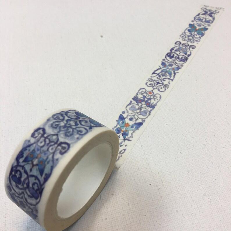 May include: A roll of decorative washi tape with a blue and white pattern featuring butterflies and floral designs. The tape is on a white background.